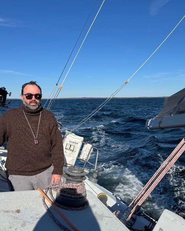 Daniel Martinez at the helm on a bright day, sailing